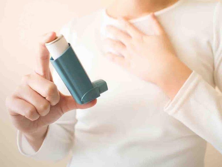 Woman holding an inhaler with her right hand
