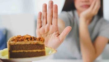 Woman put her right hand up to reject a chocolate cake in front of her