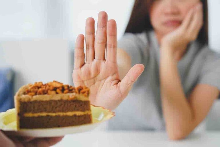 Woman put her right hand up to reject a chocolate cake in front of her