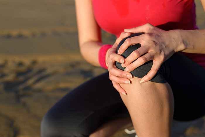 A woman holding her knee tightly due to pain in her joints