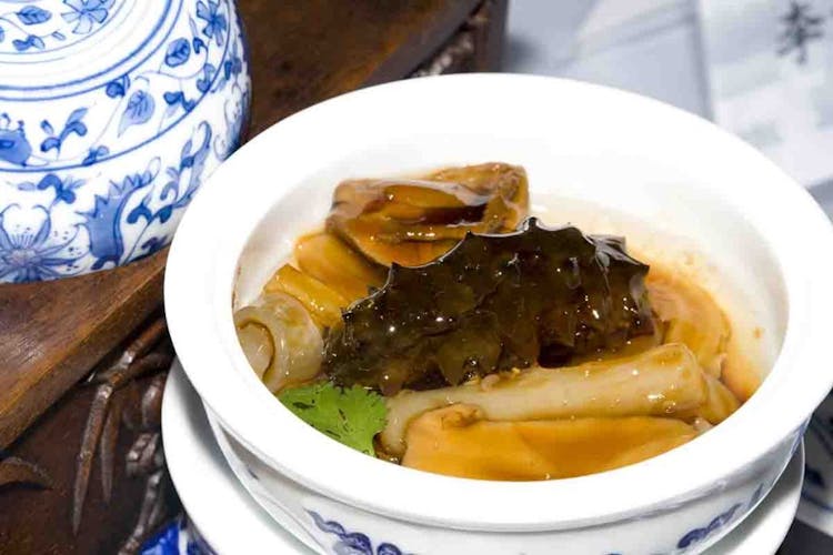 A dish that includes sea cucumber in a white bowl 