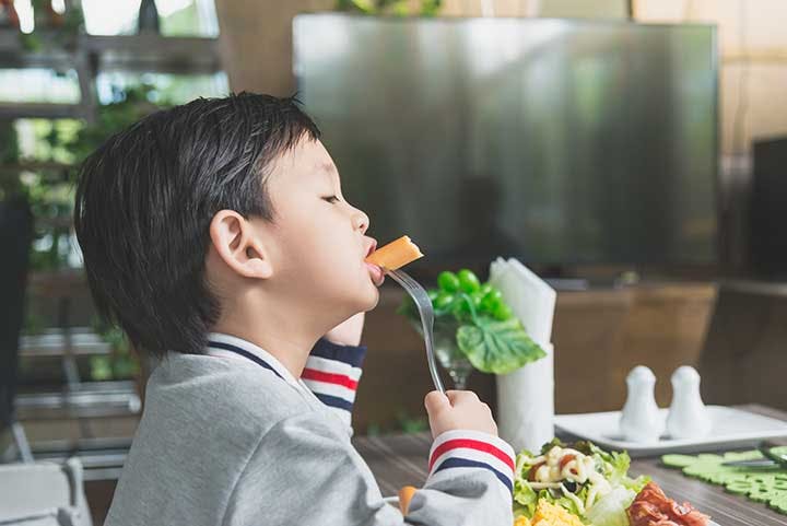 A child eating a piece of carrot