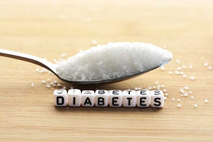 A spoon of sugar and block letters that spell ‘DIABETES’ on a wooden surface.