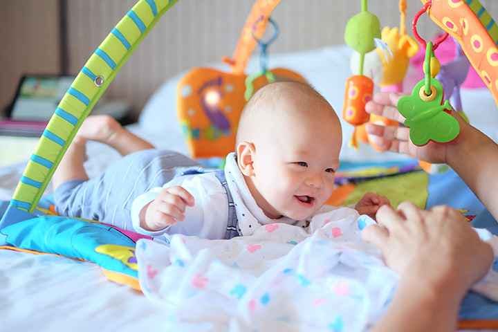 A cute 6-month-old Asian baby playing with a colourful toy arch that can prevent future eye problems.
