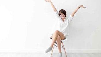 Woman sits in chair and throw up arms happily