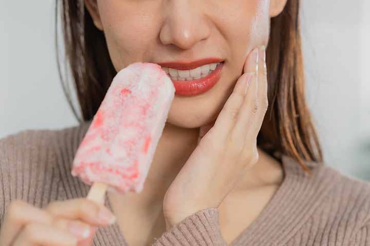 Woman looking uncomfortable while eating an ice-cream.