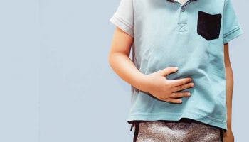 Little boy wearing blue shirt holds upset stomach with one hand