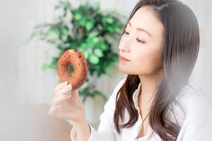 A side view of a woman staring at a doughnut
