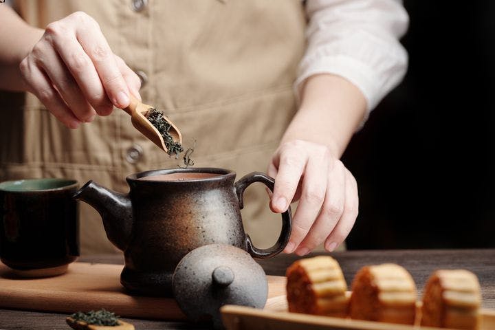 Man preparing some green tea leaves in a clay teapot for brewing