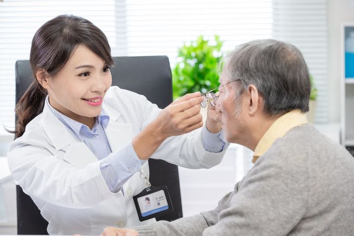 A woman doctor helping an elderly patient with his glasses