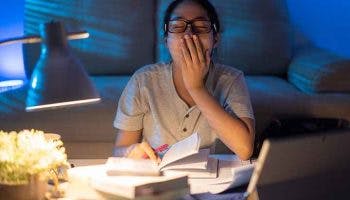 A woman yawning while working at home at night.