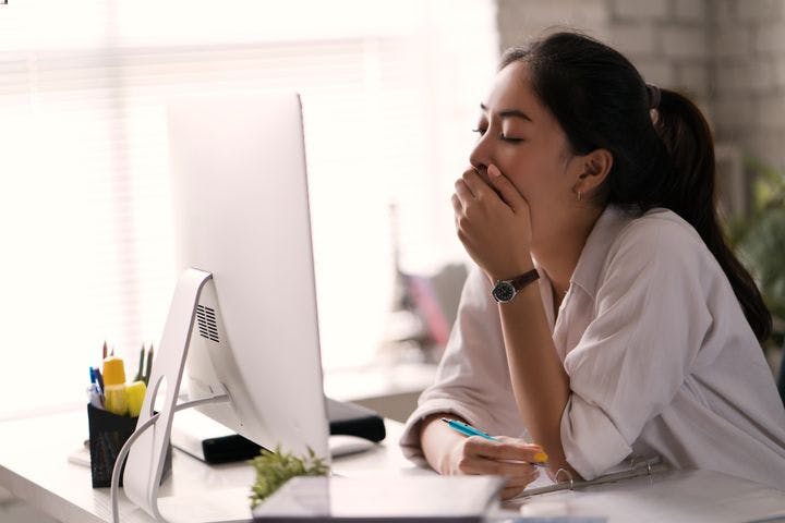 Woman yawning while looking at computer