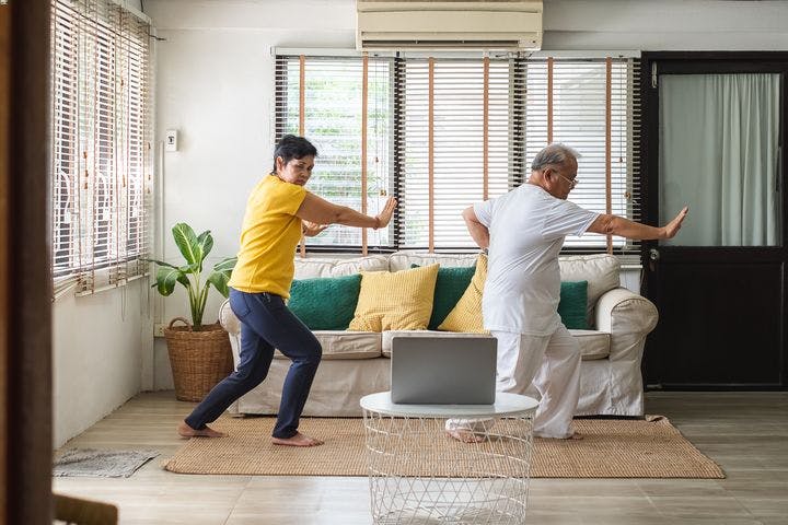 Older couple practicing tai chi in their living room