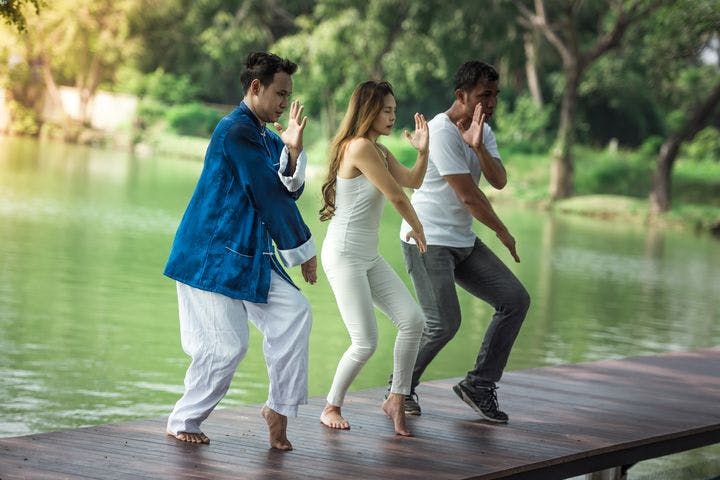 A group of young people practising Qigong in the morning by the lake