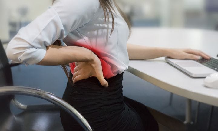 Woman stretching up on a chair with back aches