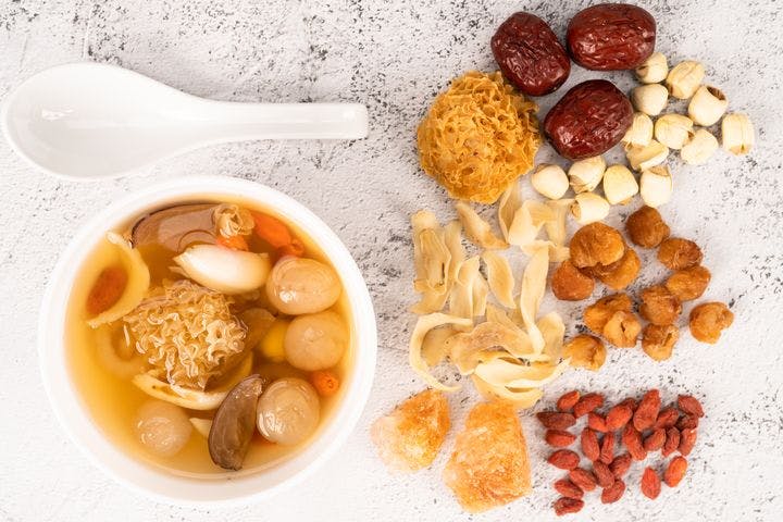 Chinese white or snow fungus dessert soup with ingredients of snow fungus, dried longan, red dates, lotus seeds, lily bulbs, goji berries and rock sugar on the side