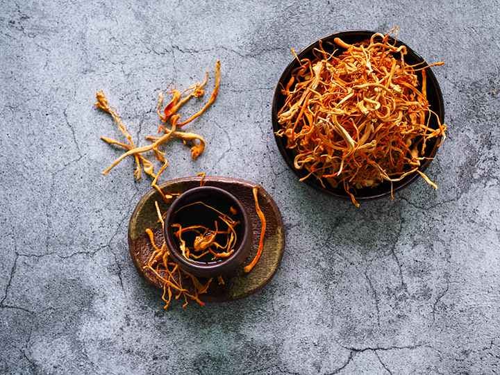 Dried cordyceps in a bowl and on a table