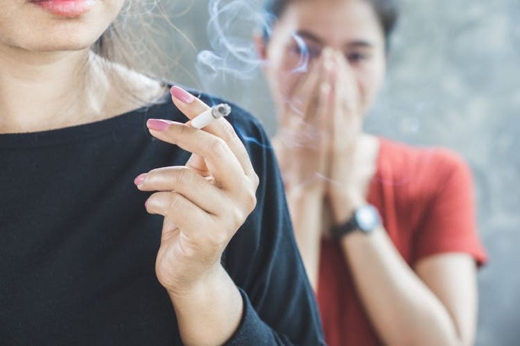 Asian woman smoking near a young girl