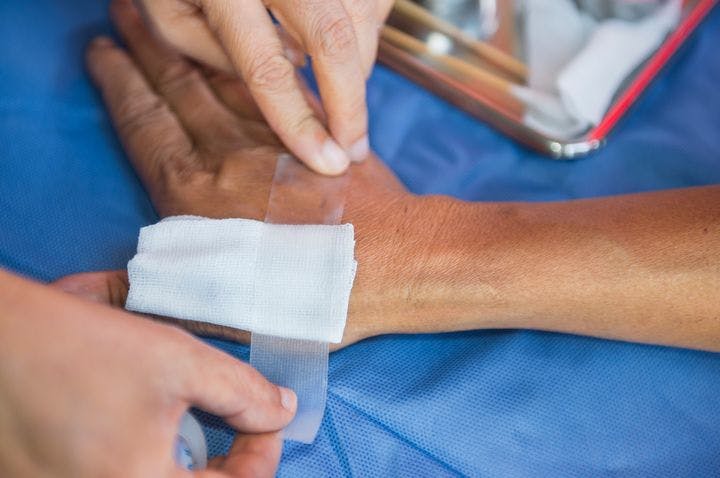 A nurse applying sterile gauze to an elderly person’s hand