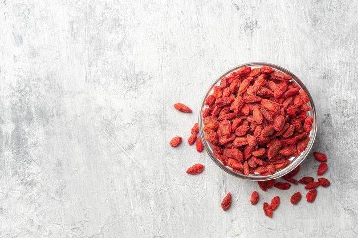 A flat-lay of dried goji berries in a glass bowl. 