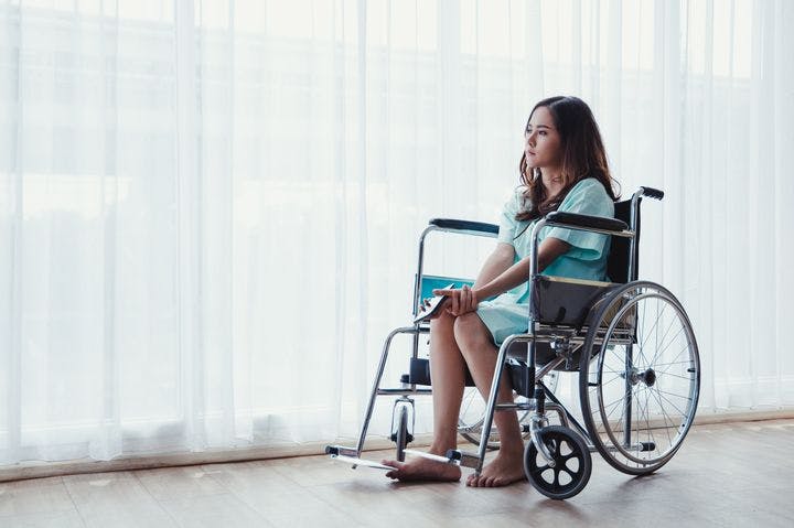 Woman sitting on a wheelchair with mobile in hand