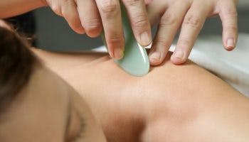 Woman getting a gua sha massage by a masseuse
