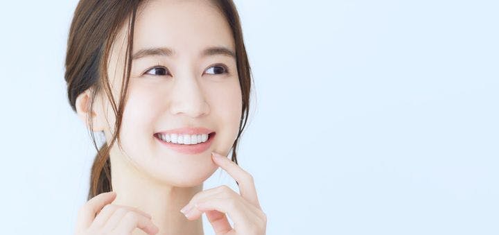 Young Asian woman with a finger near her smile, thinking of dental care concepts