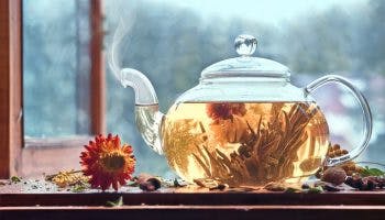 Smoking glass teapot with leaves and flowers steeping 