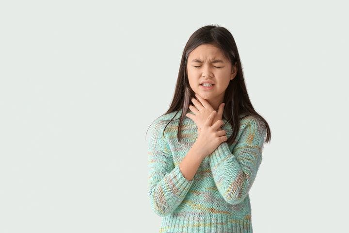Teenage girl holding the neck in pain due to sore throat