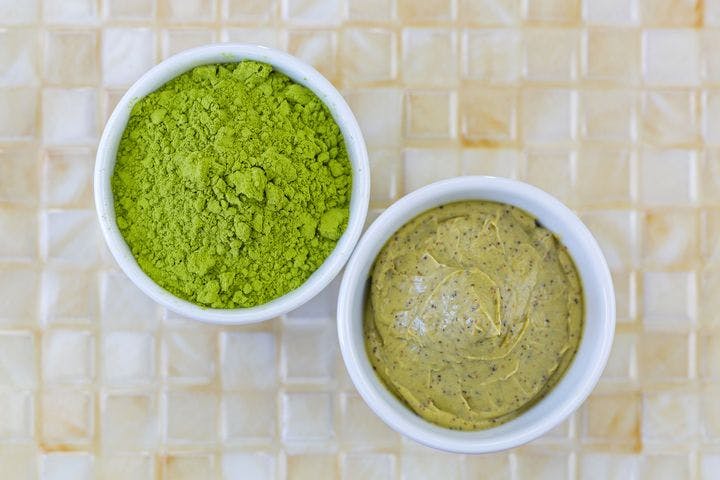 An aerial view of a bowl of green tea powder and a bowl of green tea cream.