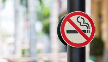 A “No Smoking” signage on both sides of a black-coloured pillar outdoors