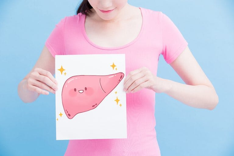 A woman in a pink shirt holding a cartoon drawing of a liver in her hand