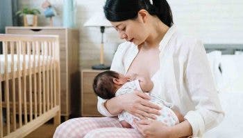Asian mother breastfeeding her newborn in the bedroom while sitting on the bed