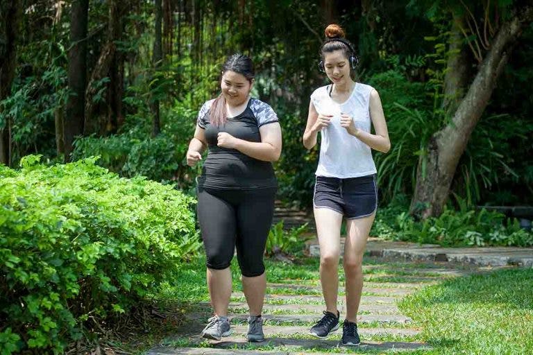 A slim woman and an overweight woman jogging at the park
