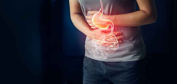 Asian person holding stomach superimposed with illustration of inflamed stomach lining