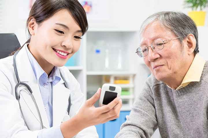 A female doctor shows blood sugar test results to an elderly patient