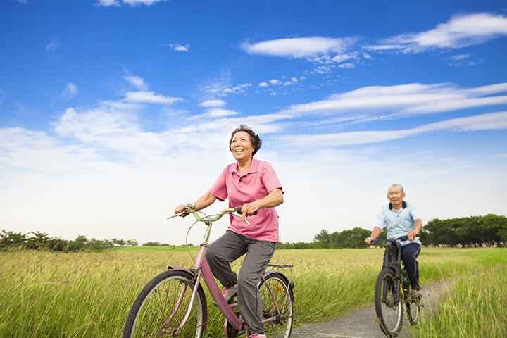 Elderly Asian couple cycling through a paddy field
