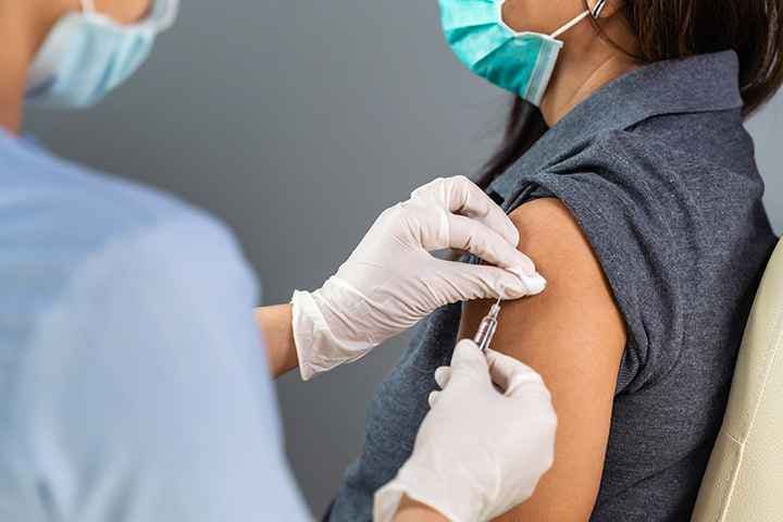 Nurse administering a COVID-19 vaccination to a woman’s left arm