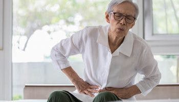 Sick elderly Asian man with belly pain with hands on his abdomen