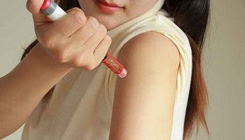 A partial view of a woman injecting insulin into her arm