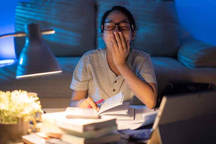 A woman yawning while working at home at night.