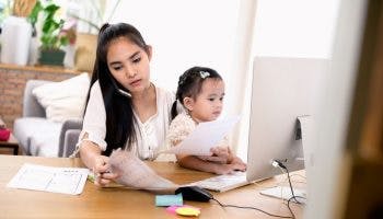 A woman at home sitting in front of a computer with her infant child on her lap