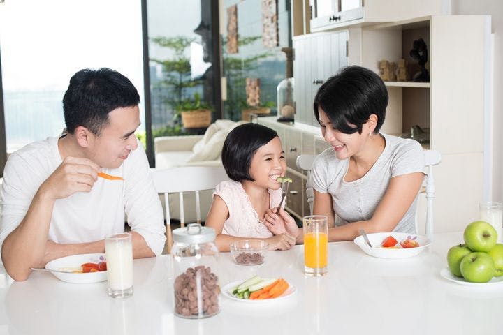 Parents and their daughter enjoying healthy breakfast together.