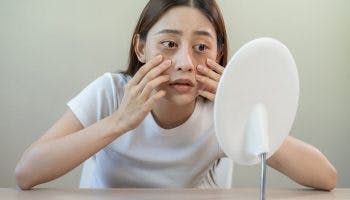 Asian woman looking into the mirror examining her eye bags