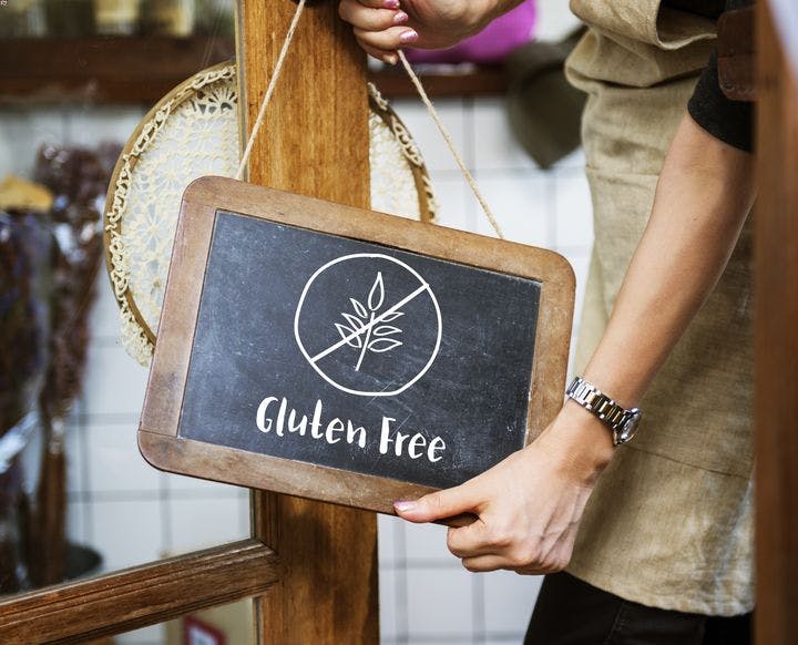 Man holding up a blackboard that says ‘Gluten Free’