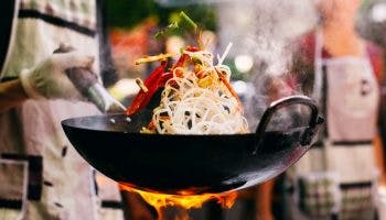 A chef swirling food around in a Chinese wok