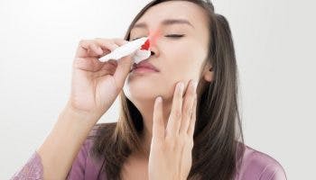 Woman attends to nosebleed with tissue