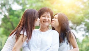 Two women kissing their elderly mother on the cheeks