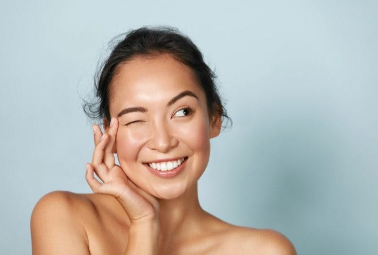 An Asian lady smiling with her right eye closed