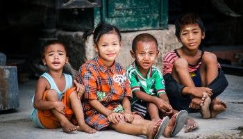 Young Asian children sitting by the roadside.